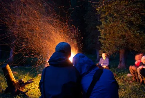 A couple is sitting by a campfire in the mountains
